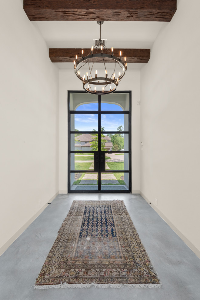 Réalisation d'un hall d'entrée tradition de taille moyenne avec un mur blanc, sol en béton ciré, une porte double, une porte en verre, un sol gris et poutres apparentes.