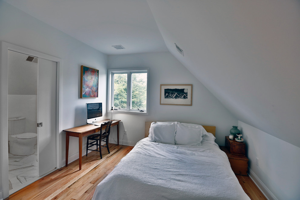 Small eclectic guest bedroom in New York with white walls and medium hardwood floors.