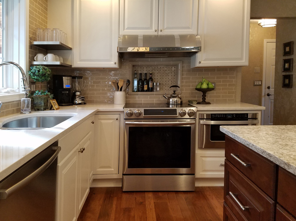 Mid-sized transitional l-shaped medium tone wood floor and brown floor eat-in kitchen photo with an undermount sink, raised-panel cabinets, white cabinets, quartz countertops, subway tile backsplash, stainless steel appliances, an island, beige backsplash and white countertops