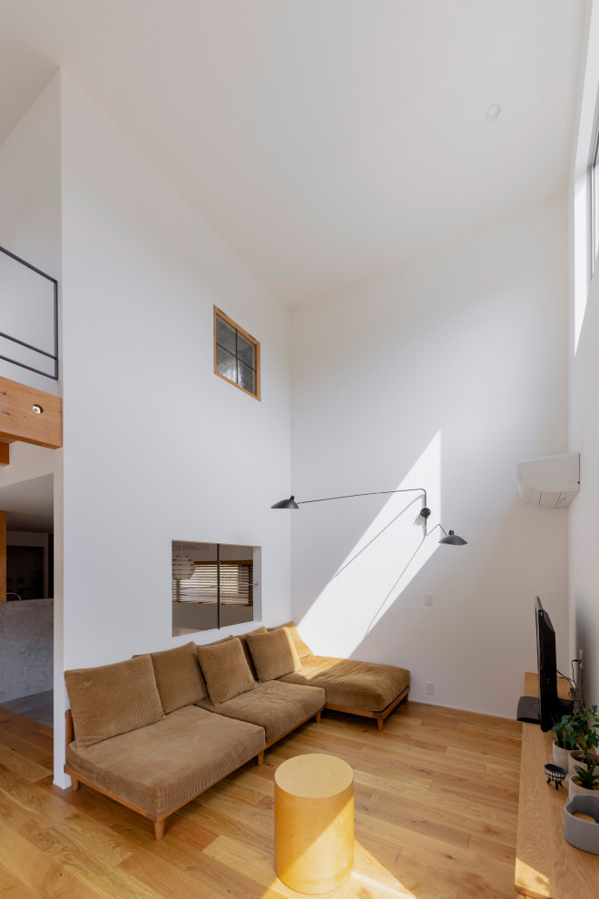 Inspiration för ett litet skandinaviskt separat vardagsrum, med ett bibliotek, vita väggar, mellanmörkt trägolv, en fristående TV och beiget golv
