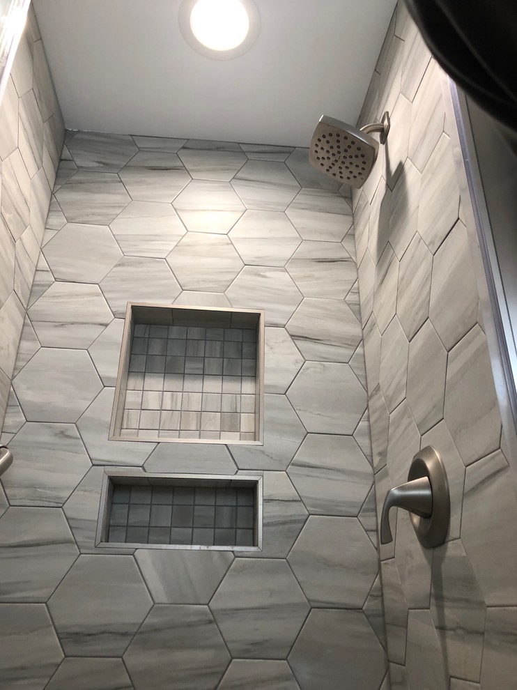 This is an example of a small transitional bathroom in Chicago with furniture-like cabinets, blue cabinets, an alcove shower, a one-piece toilet, gray tile, porcelain tile, grey walls, porcelain floors, an integrated sink, solid surface benchtops, grey floor, a hinged shower door and white benchtops.