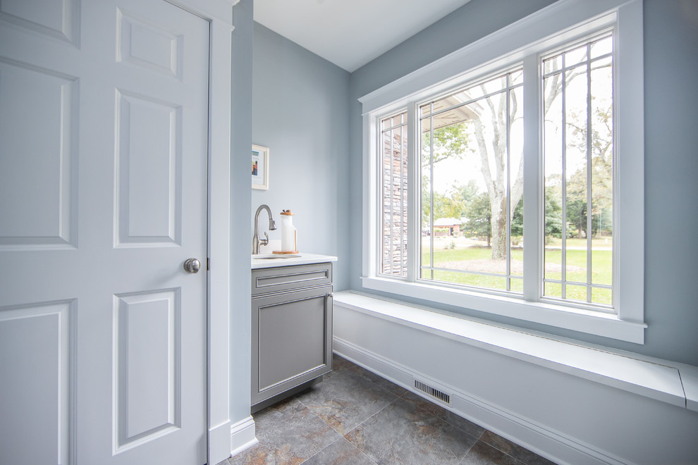 This is an example of a mid-sized traditional dedicated laundry room in DC Metro with an undermount sink, shaker cabinets, grey cabinets, quartz benchtops, grey walls, porcelain floors, a concealed washer and dryer, multi-coloured floor and white benchtop.