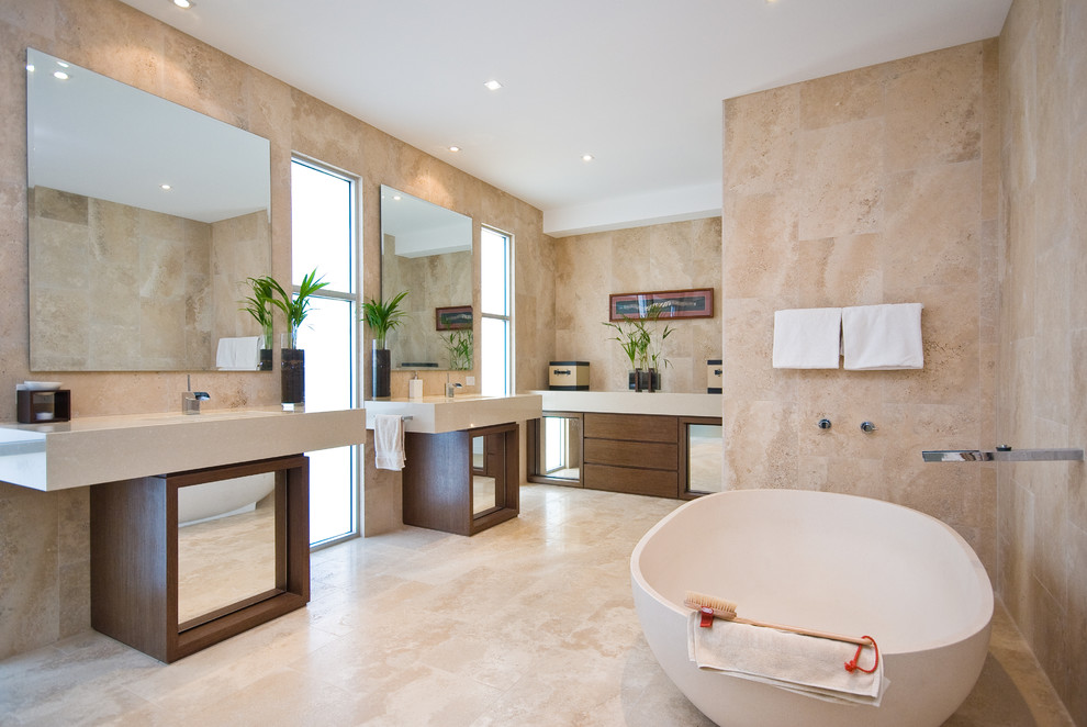 This is an example of a contemporary master bathroom in Brisbane with medium wood cabinets, a freestanding tub, beige tile and flat-panel cabinets.