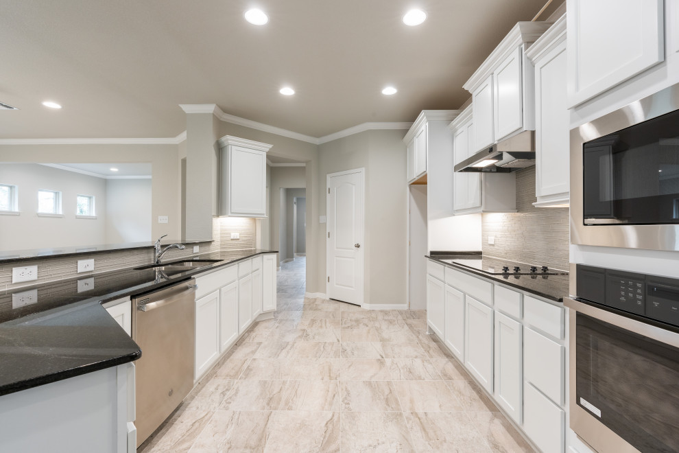 Large arts and crafts galley kitchen pantry in Austin with an undermount sink, recessed-panel cabinets, beige cabinets, quartzite benchtops, grey splashback, glass tile splashback, stainless steel appliances, ceramic floors, a peninsula, beige floor and black benchtop.