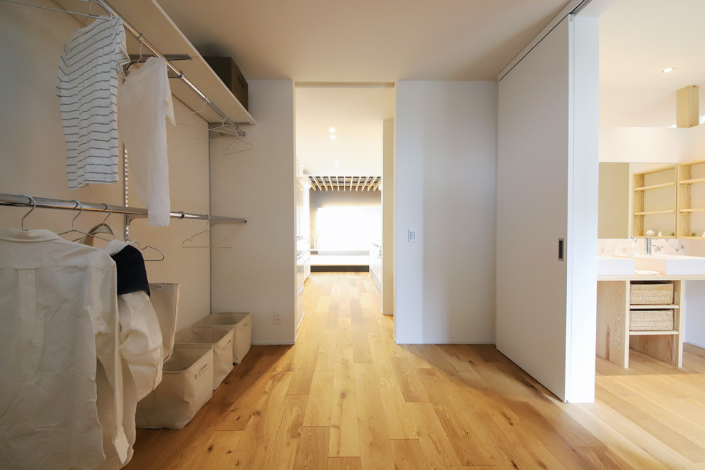 Neutrales Modernes Ankleidezimmer mit Ankleidebereich, offenen Schränken, Sperrholzboden, braunem Boden und Tapetendecke in Sonstige