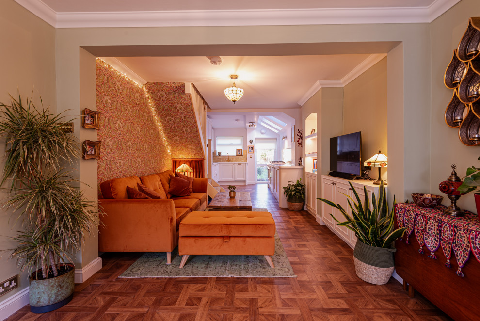 Réalisation d'un salon bohème de taille moyenne et ouvert avec un mur vert, sol en stratifié, un téléviseur encastré, un sol marron, un plafond en papier peint et du papier peint.