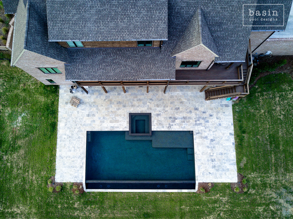 Example of a large transitional backyard stone and custom-shaped infinity hot tub design in Nashville