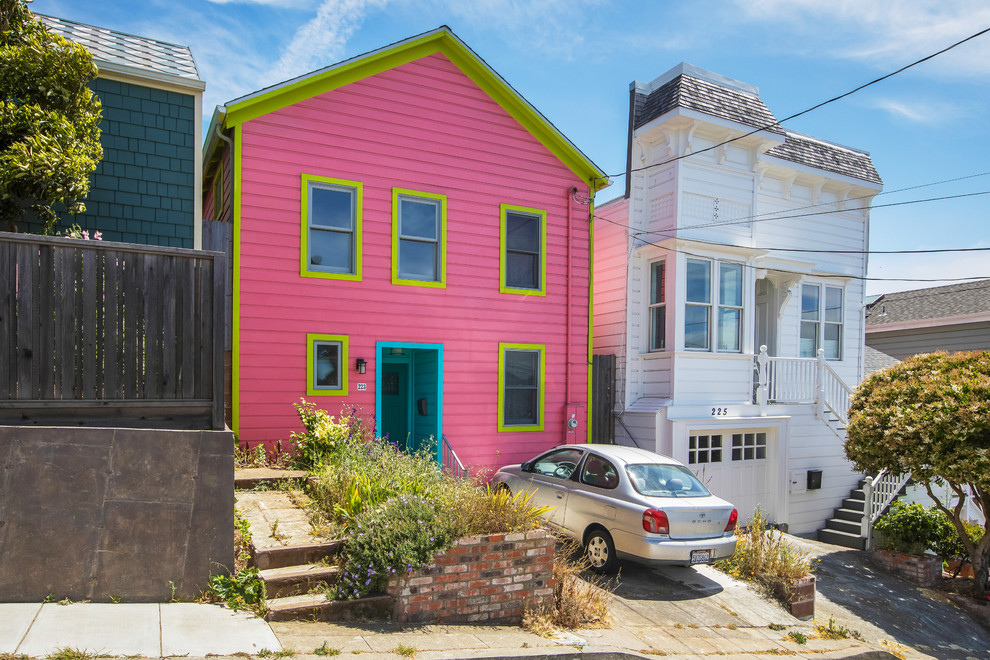 Mid-sized eclectic three-storey pink house exterior in San Francisco with wood siding, a gable roof and a shingle roof.