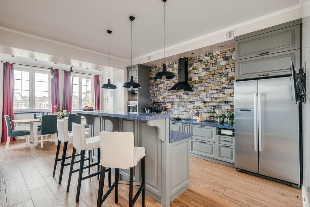 Design ideas for a large eclectic galley eat-in kitchen in Moscow with a farmhouse sink, raised-panel cabinets, grey cabinets, solid surface benchtops, blue splashback, ceramic splashback, panelled appliances, porcelain floors, with island, brown floor and blue benchtop.