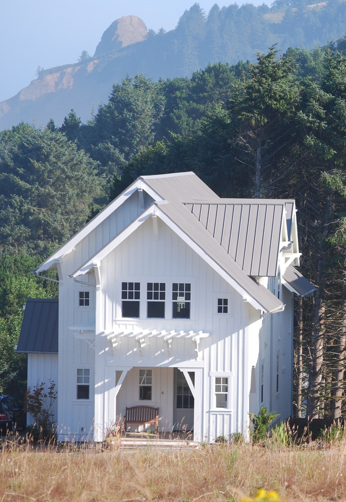 This is an example of a large country two-storey white exterior in Portland with wood siding, a gable roof and a metal roof.
