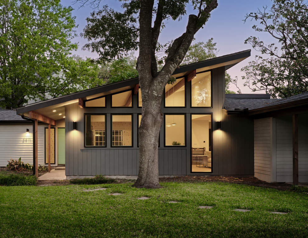 This is an example of a mid-sized midcentury one-storey concrete black house exterior in Austin with a butterfly roof, a shingle roof, a black roof and clapboard siding.
