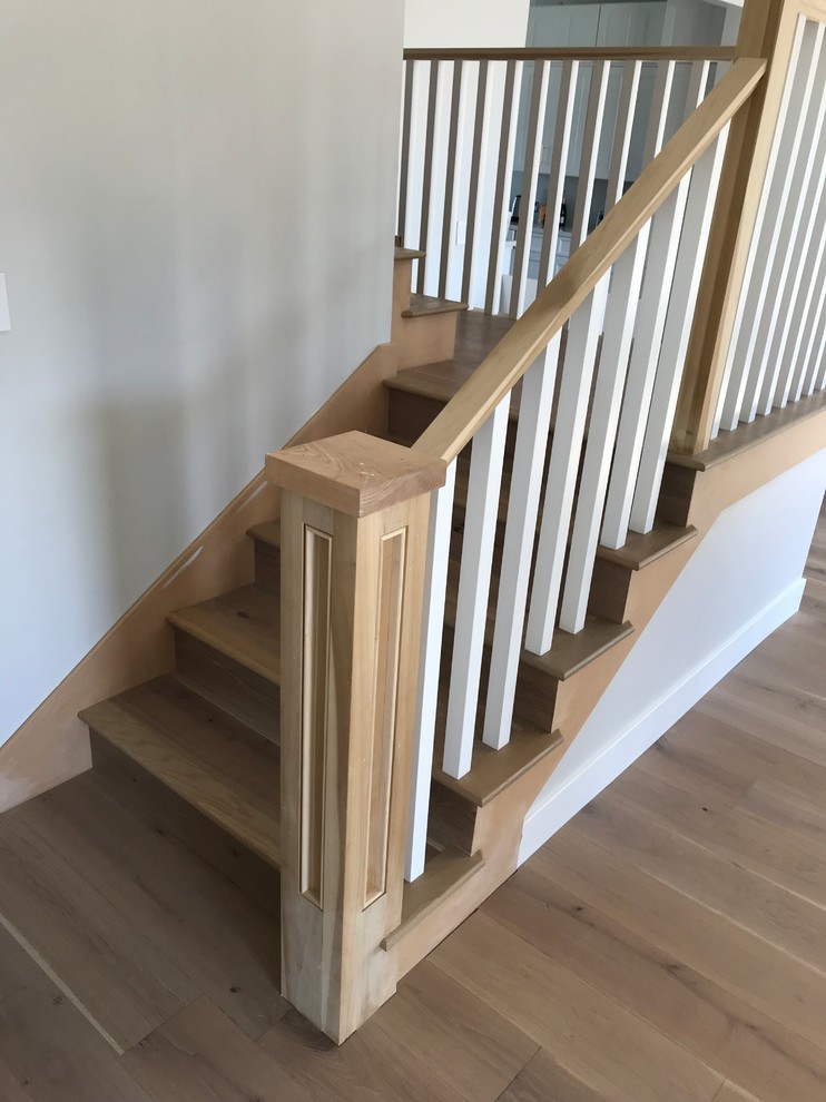 This is an example of a mid-sized beach style wood u-shaped staircase in Orange County with wood risers and wood railing.