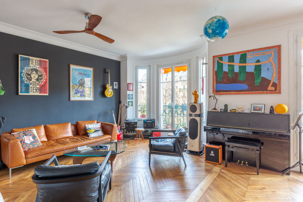 Photo of an eclectic living room in Paris with black walls, medium hardwood floors and brown floor.