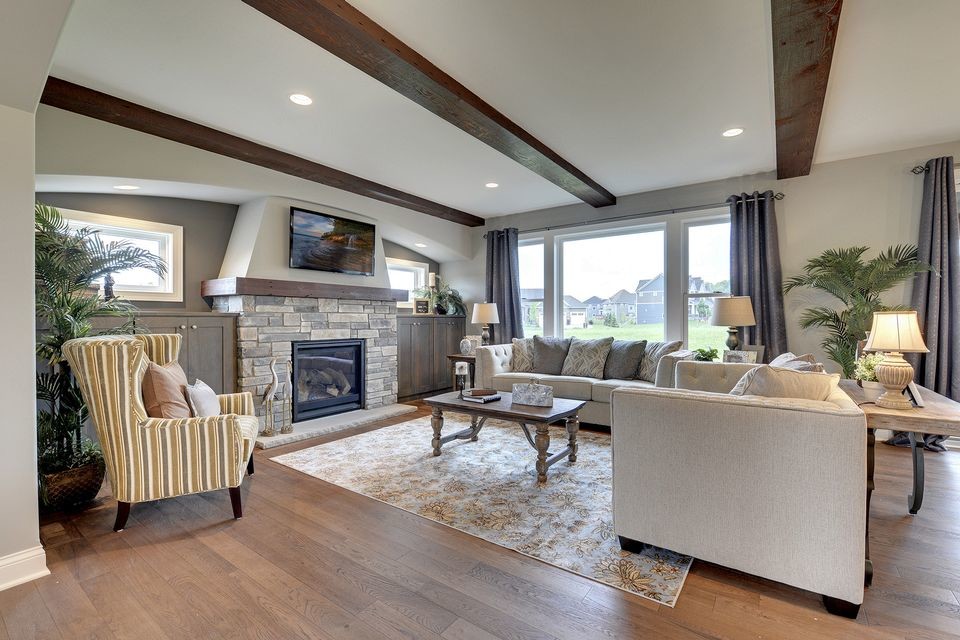 This is an example of a large transitional loft-style family room in Minneapolis with grey walls, medium hardwood floors, a standard fireplace, a stone fireplace surround and a built-in media wall.