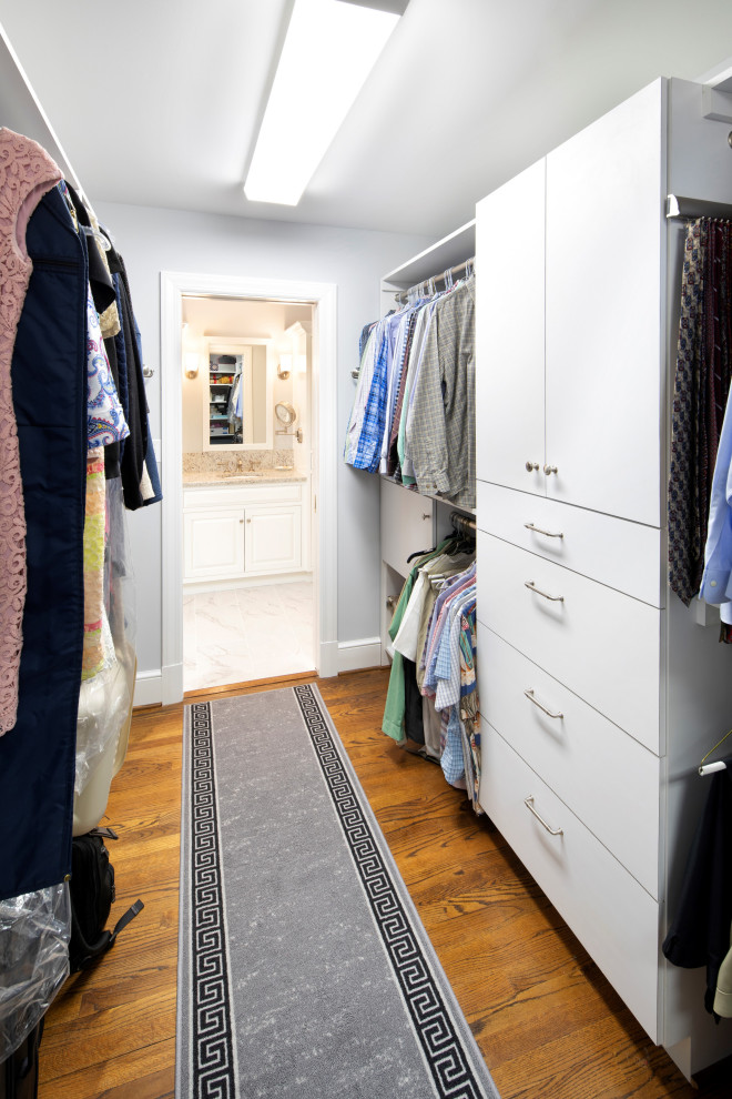 Modelo de armario vestidor unisex con armarios con paneles lisos, puertas de armario blancas, suelo de madera en tonos medios y suelo marrón