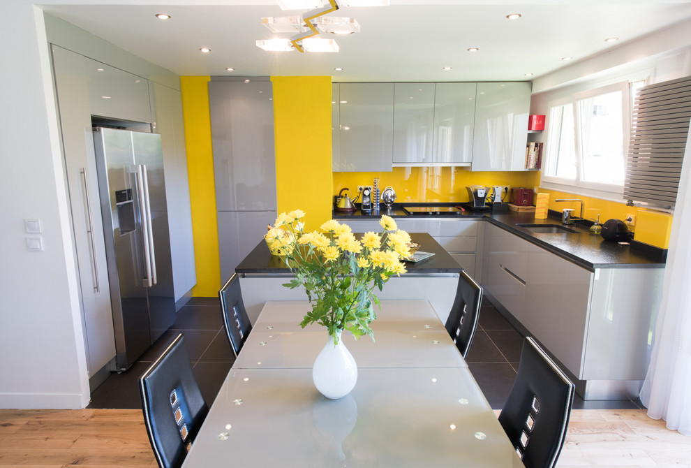 Inspiration for a mid-sized eclectic u-shaped eat-in kitchen in Paris with an integrated sink, louvered cabinets, grey cabinets, granite benchtops, glass tile splashback, white appliances, multiple islands and yellow splashback.
