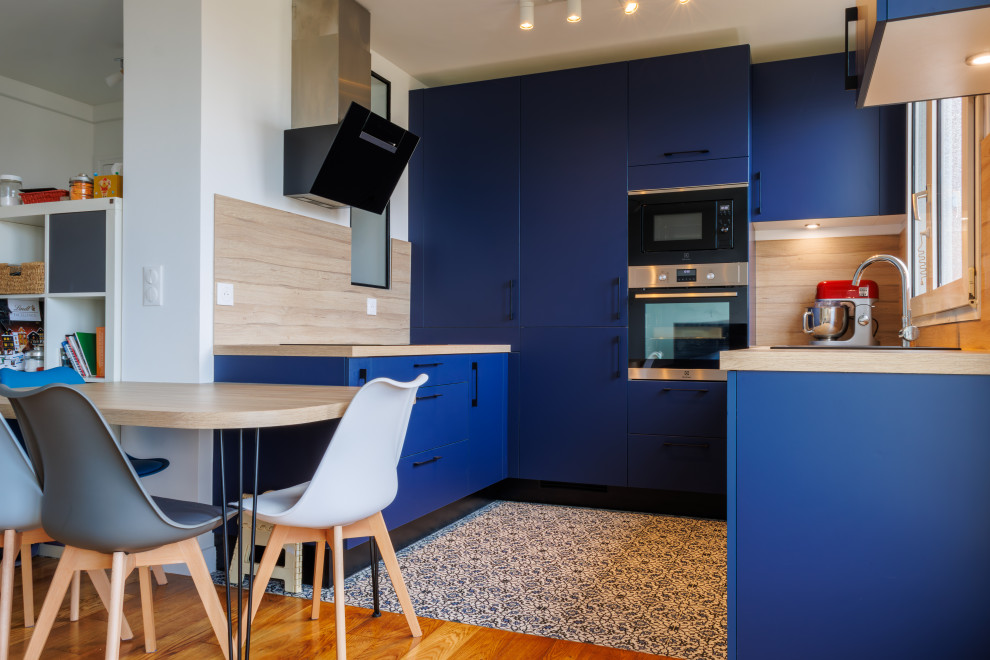 Exempel på ett litet modernt beige beige kök, med en undermonterad diskho, luckor med infälld panel, blå skåp, träbänkskiva, beige stänkskydd, stänkskydd i trä, integrerade vitvaror, cementgolv och blått golv