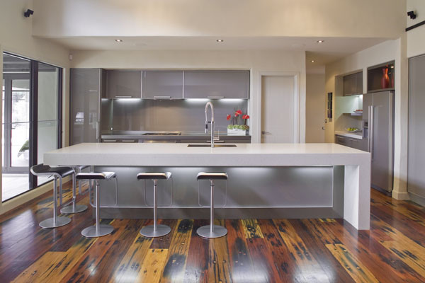 Inspiration for a large modern l-shaped eat-in kitchen in Los Angeles with an undermount sink, flat-panel cabinets, grey cabinets, quartz benchtops, grey splashback, glass sheet splashback, panelled appliances, medium hardwood floors and with island.