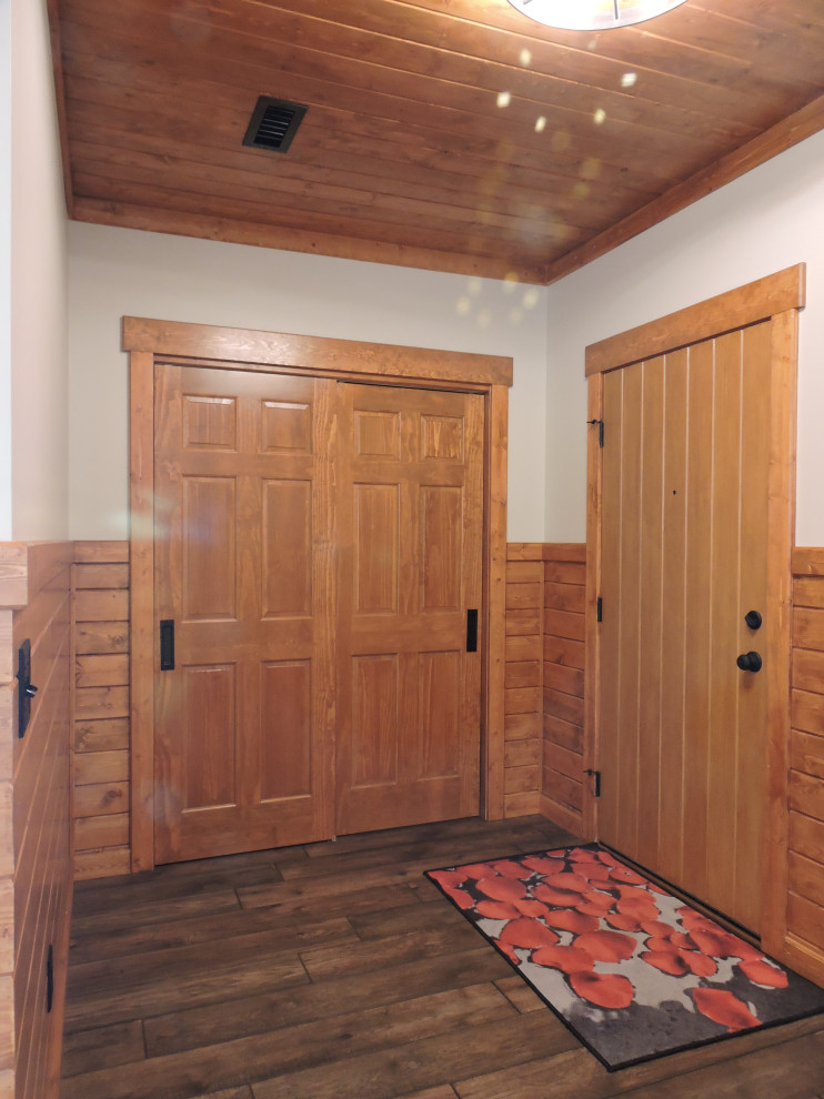 Uriges Foyer mit beiger Wandfarbe, Vinylboden, Einzeltür, hellbrauner Holzhaustür, braunem Boden, Holzdecke und Holzwänden in Sonstige