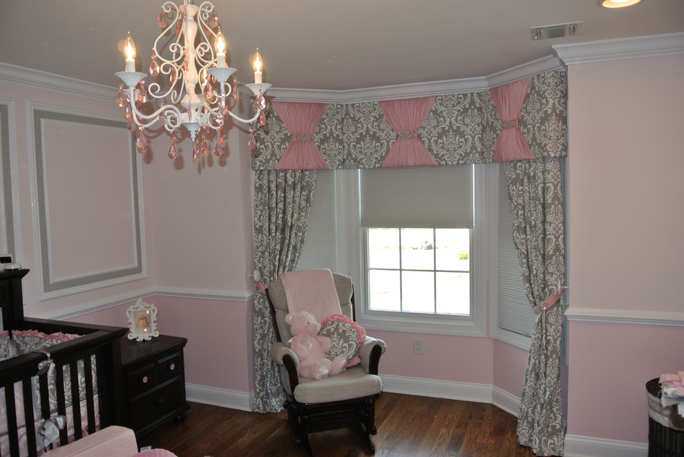 Design ideas for a mid-sized traditional nursery for girls in New York with pink walls, dark hardwood floors and brown floor.