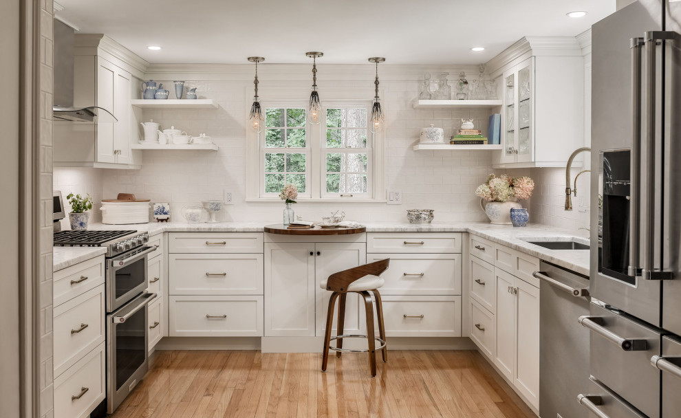 Inspiration for a small transitional u-shaped separate kitchen in Portland Maine with an undermount sink, recessed-panel cabinets, white cabinets, quartzite benchtops, white splashback, subway tile splashback, stainless steel appliances, medium hardwood floors, no island, brown floor and grey benchtop.