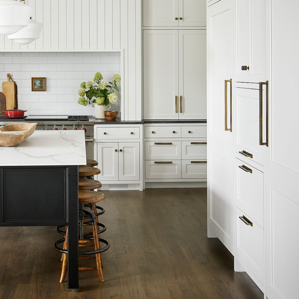 Photo of a large beach style u-shaped eat-in kitchen in Chicago with shaker cabinets, white cabinets, white splashback, stainless steel appliances, dark hardwood floors, with island, brown floor and multi-coloured benchtop.
