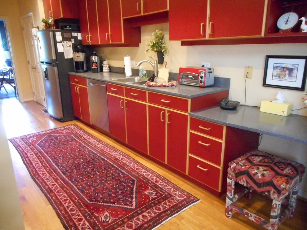 Inspiration for a mid-sized rustic single-wall light wood floor and beige floor enclosed kitchen remodel with a double-bowl sink, flat-panel cabinets, red cabinets, solid surface countertops, stainless steel appliances and no island