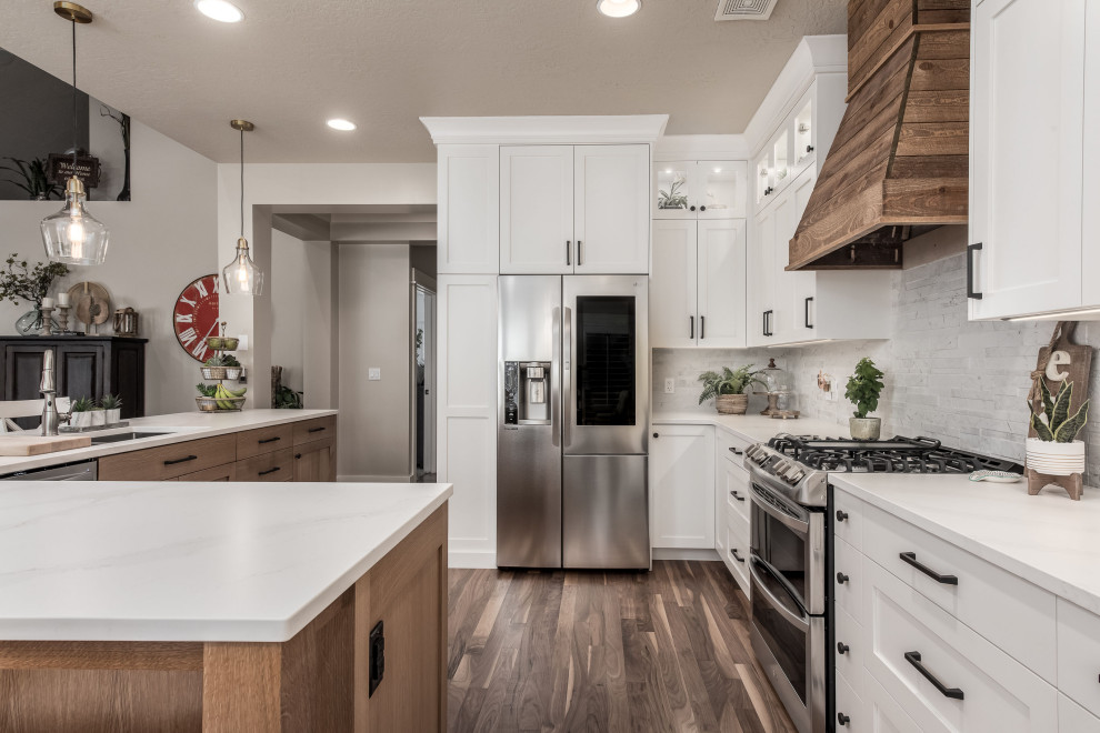 Mid-sized country l-shaped eat-in kitchen in Salt Lake City with a drop-in sink, shaker cabinets, white cabinets, quartz benchtops, white splashback, stone tile splashback, stainless steel appliances, medium hardwood floors, with island and white benchtop.