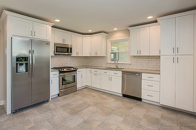 Open concept kitchen - mid-sized transitional l-shaped gray floor open concept kitchen idea in Chicago with an undermount sink, shaker cabinets, white cabinets, white backsplash, subway tile backsplash, stainless steel appliances and no island