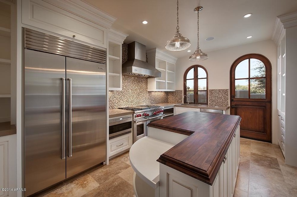 Example of a mid-sized transitional l-shaped porcelain tile enclosed kitchen design in Phoenix with an undermount sink, raised-panel cabinets, white cabinets, solid surface countertops, beige backsplash, mosaic tile backsplash, stainless steel appliances and an island