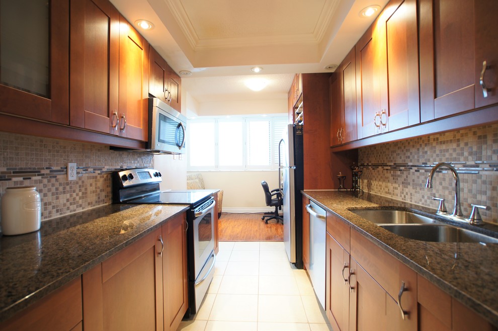 Example of a mid-sized transitional galley ceramic tile enclosed kitchen design in Toronto with an undermount sink, shaker cabinets, medium tone wood cabinets, granite countertops, beige backsplash, mosaic tile backsplash, stainless steel appliances and no island