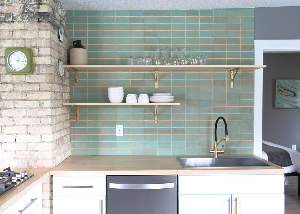 Open concept kitchen - small transitional l-shaped light wood floor and brown floor open concept kitchen idea in Minneapolis with a drop-in sink, flat-panel cabinets, white cabinets, wood countertops, green backsplash, ceramic backsplash, stainless steel appliances, no island and brown countertops