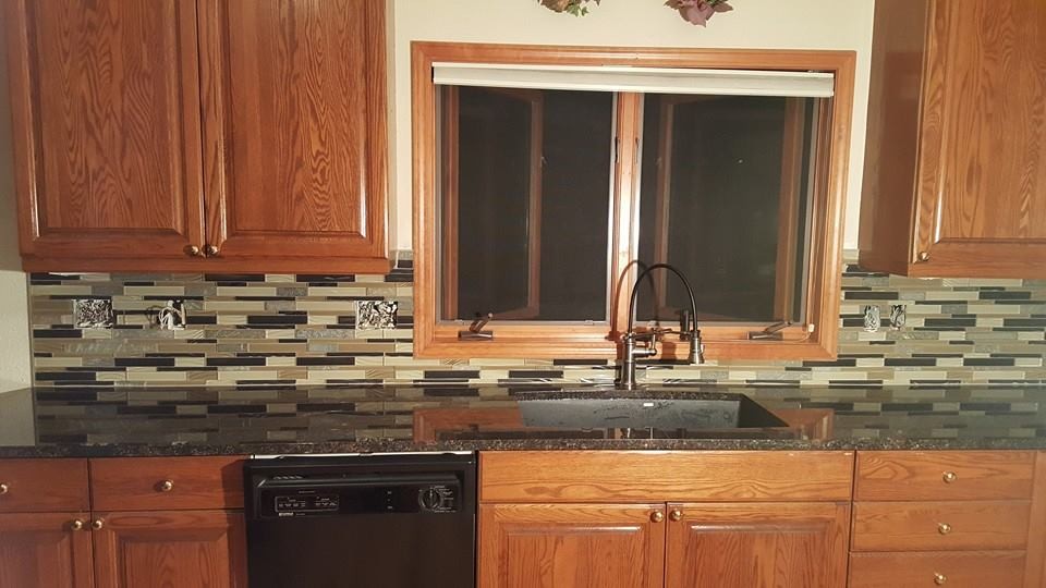 Mid-sized elegant kitchen pantry photo with an undermount sink, raised-panel cabinets, medium tone wood cabinets, multicolored backsplash, matchstick tile backsplash, black appliances and no island