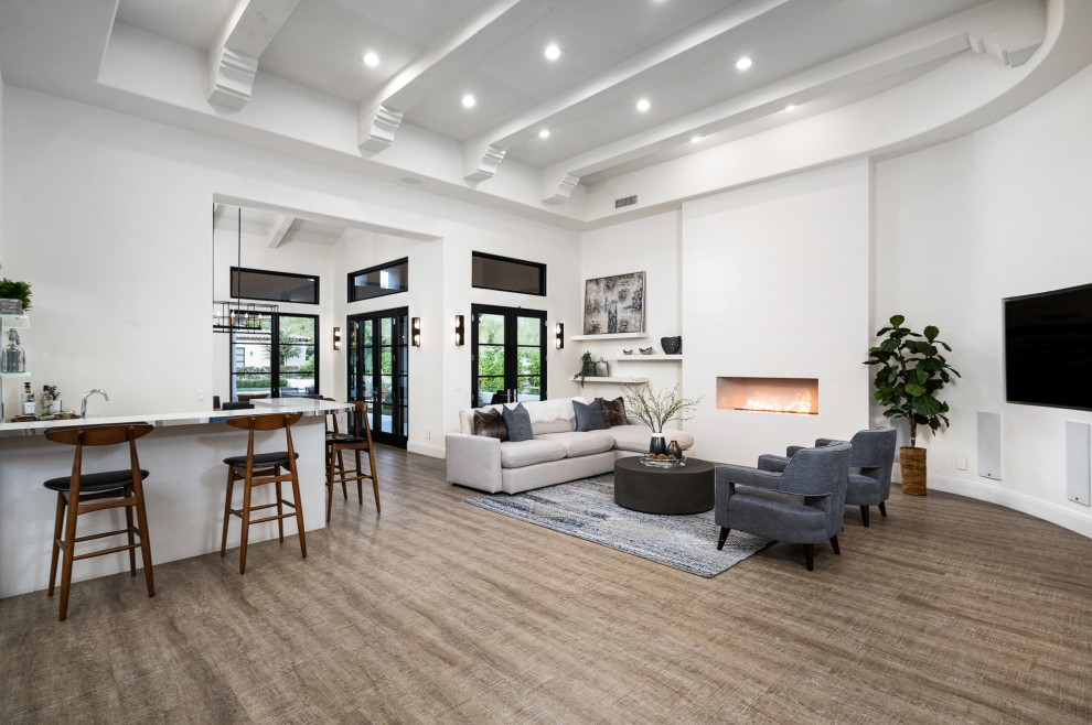 Ispirazione per un ampio soggiorno moderno aperto con pareti bianche, angolo bar, pavimento in laminato, pavimento beige e travi a vista