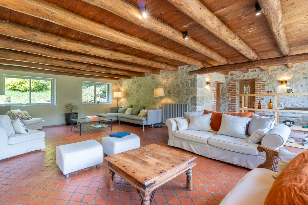 Diseño de salón campestre con paredes beige, suelo de baldosas de terracota, suelo naranja, vigas vistas y madera