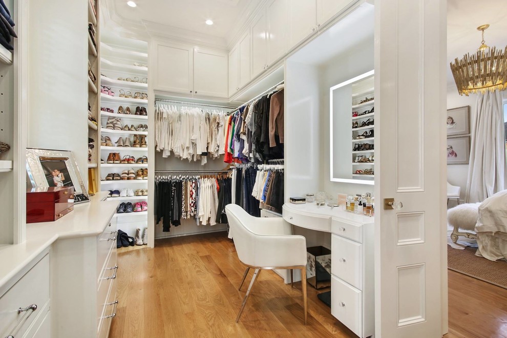 Photo of a large contemporary women's walk-in wardrobe in New Orleans with flat-panel cabinets, white cabinets, medium hardwood floors and brown floor.