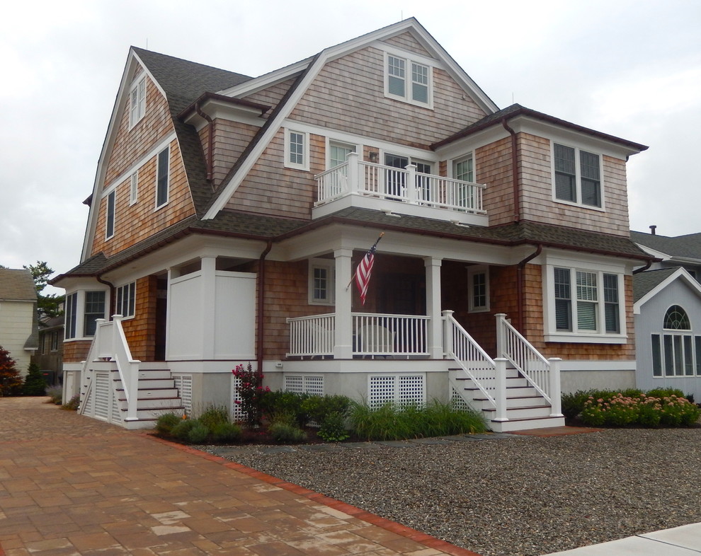 Photo of a mid-sized beach style three-storey beige house exterior in New York with wood siding, a gambrel roof and a shingle roof.