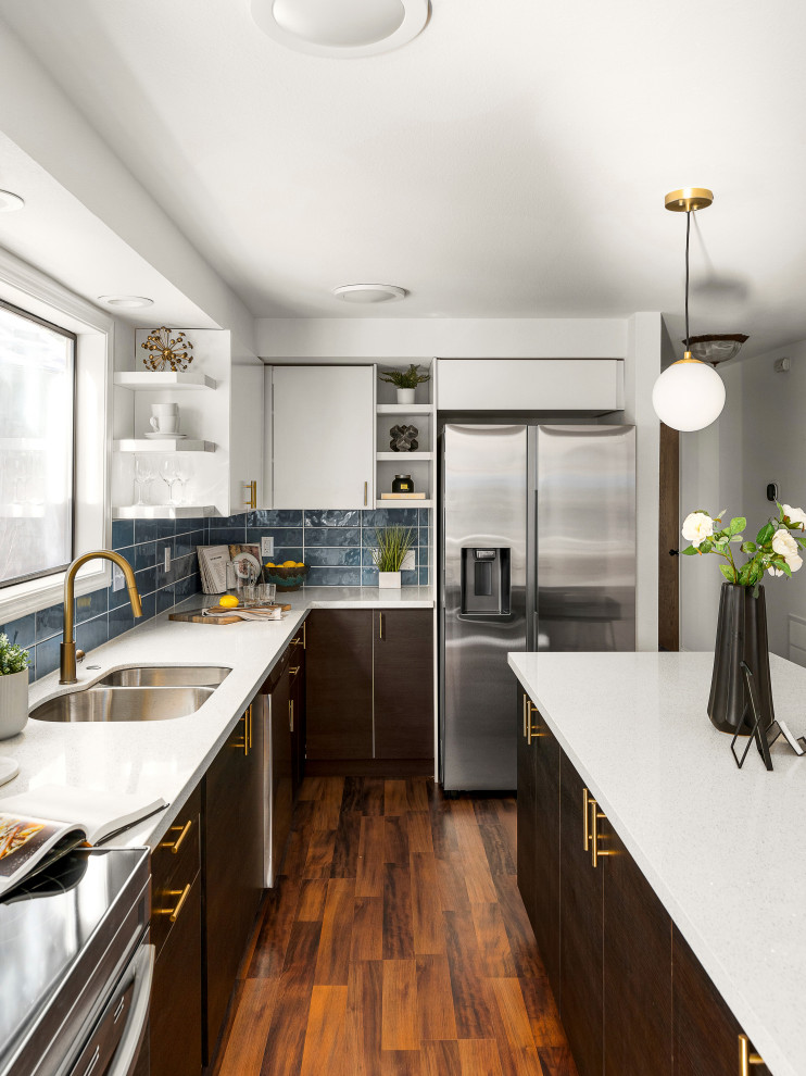 Inspiration for a contemporary l-shaped kitchen in Portland with a double-bowl sink, flat-panel cabinets, dark wood cabinets, blue splashback, stainless steel appliances, dark hardwood floors, with island, brown floor and white benchtop.