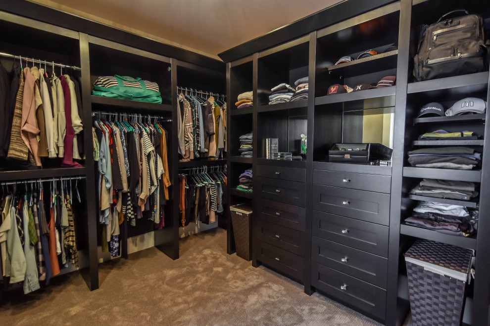 Design ideas for a modern gender-neutral walk-in wardrobe in Edmonton with shaker cabinets, dark wood cabinets and carpet.