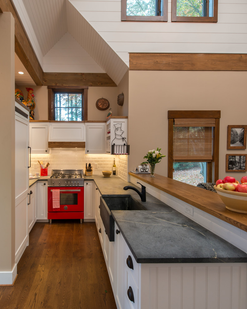 Design ideas for a small country u-shaped open plan kitchen in Boston with a farmhouse sink, shaker cabinets, white cabinets, soapstone benchtops, white splashback, subway tile splashback, coloured appliances, a peninsula and dark hardwood floors.