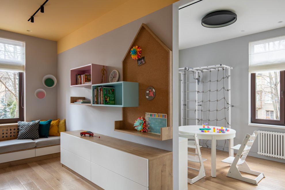 Foto di una cameretta per bambini da 4 a 10 anni contemporanea di medie dimensioni con pareti multicolore, pavimento in legno massello medio e pavimento marrone