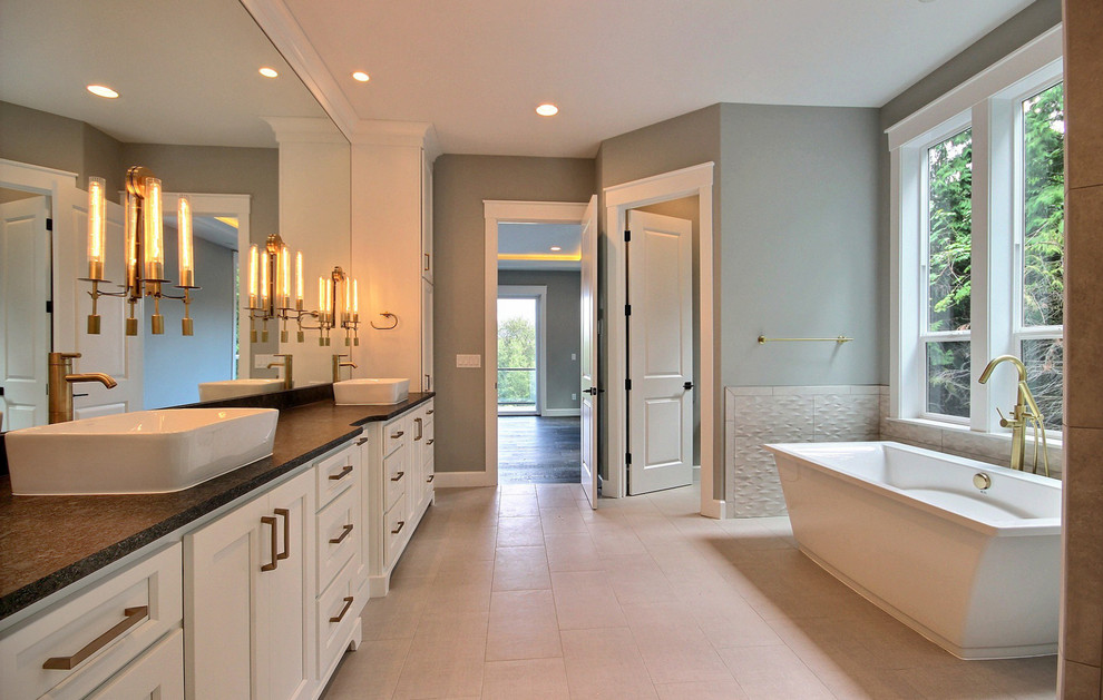 Photo of an expansive arts and crafts master bathroom in Portland with shaker cabinets, white cabinets, a freestanding tub, a double shower, a bidet, beige tile, ceramic tile, grey walls, ceramic floors, a pedestal sink, engineered quartz benchtops, beige floor, a hinged shower door and black benchtops.