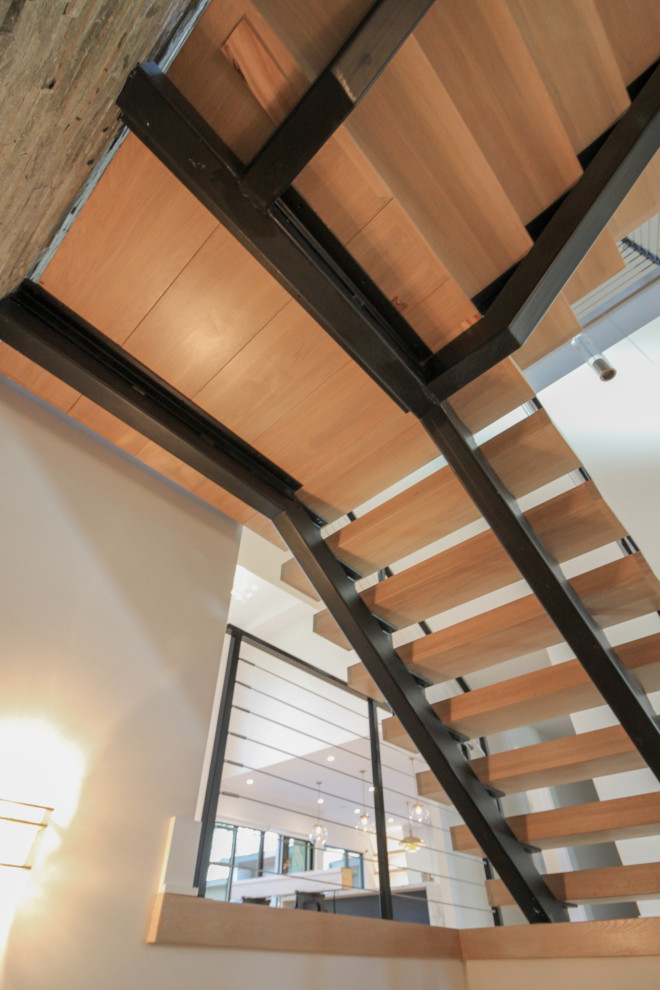 Imagen de escalera suspendida bohemia grande con escalones de madera, barandilla de metal y ladrillo
