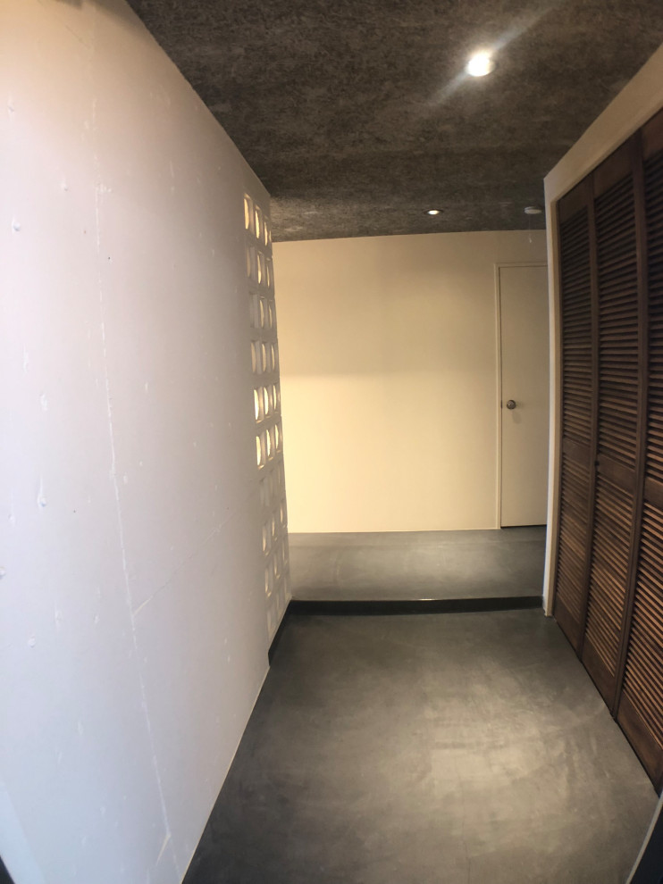 Cette image montre une petite entrée minimaliste avec un couloir, un mur blanc, sol en béton ciré, un sol gris, un plafond en lambris de bois et du lambris de bois.
