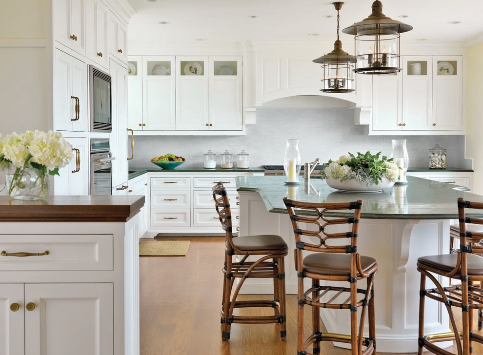 This is an example of a large beach style l-shaped separate kitchen in Boston with recessed-panel cabinets, white cabinets, white splashback, subway tile splashback, stainless steel appliances, marble benchtops, with island, light hardwood floors, beige floor and green benchtop.