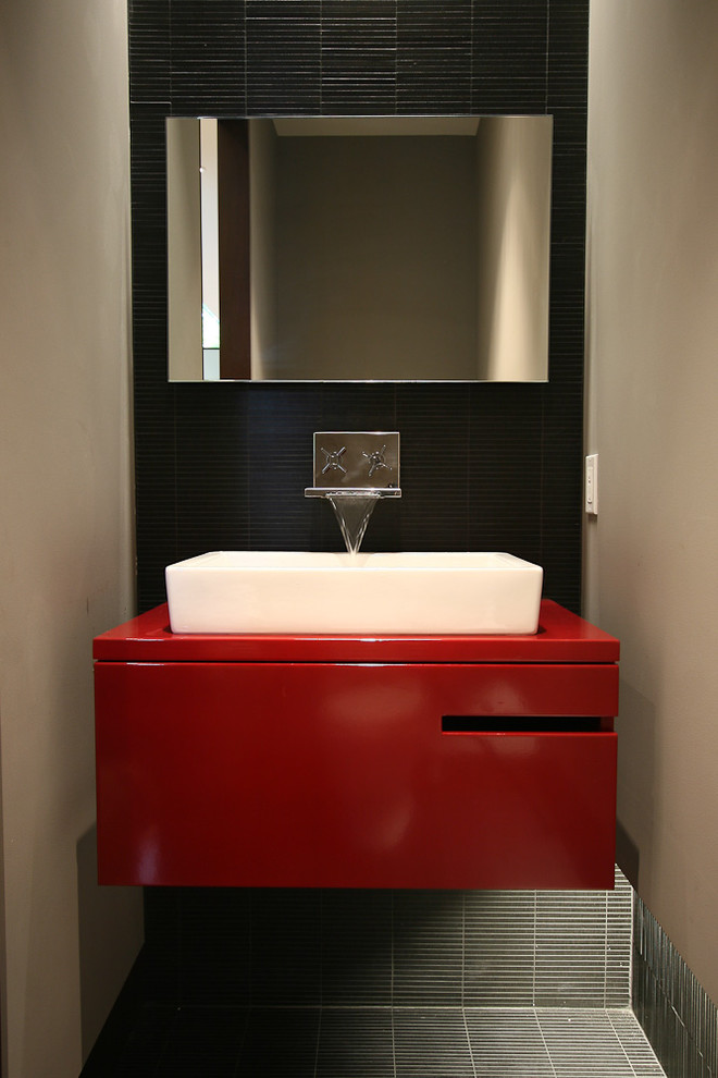 Photo of a contemporary bathroom in Grand Rapids with a vessel sink, red cabinets, black tile and red benchtops.