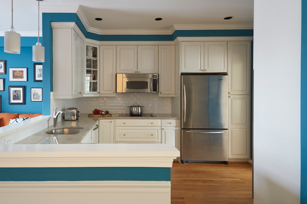 Inspiration for an u-shaped medium tone wood floor open concept kitchen remodel in Baltimore with an undermount sink, white cabinets, marble countertops, white backsplash, subway tile backsplash and stainless steel appliances