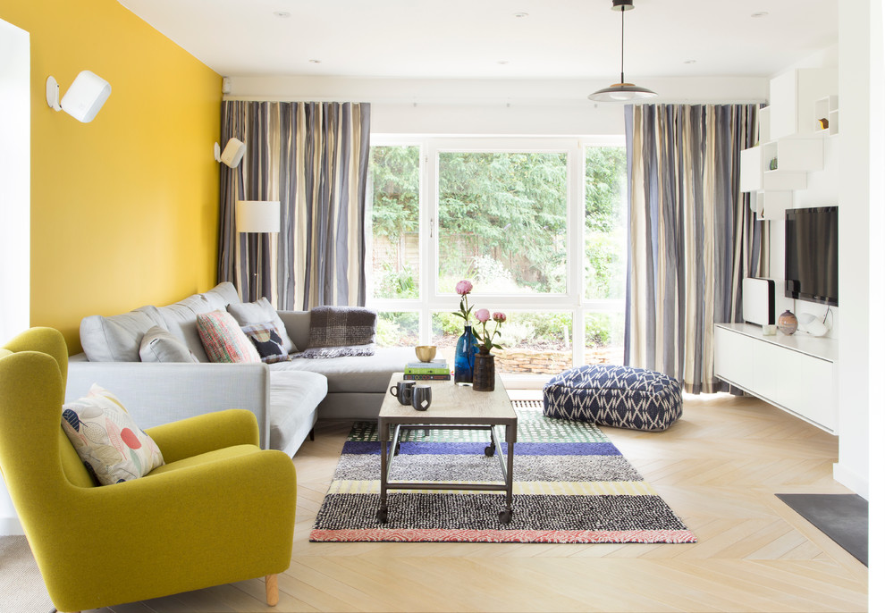 Contemporary living room in London with yellow walls and light hardwood floors.