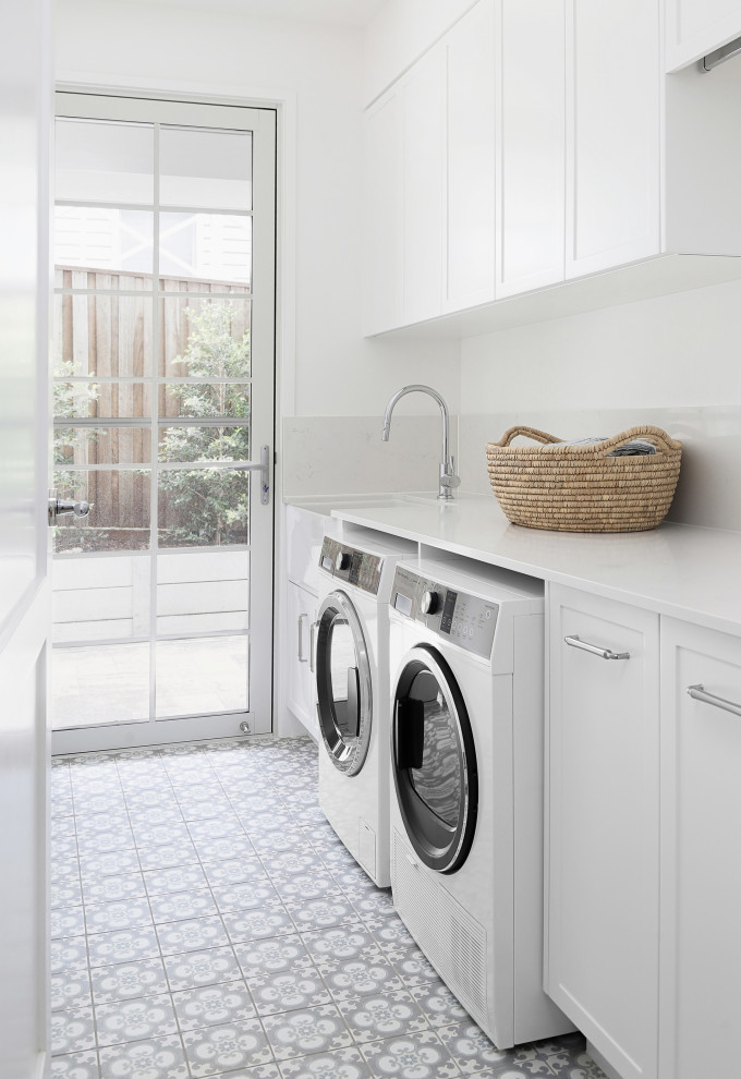 Inspiration for a mid-sized beach style galley dedicated laundry room in Sunshine Coast with white cabinets, quartz benchtops, ceramic splashback, white walls, ceramic floors, a side-by-side washer and dryer, multi-coloured floor and white benchtop.