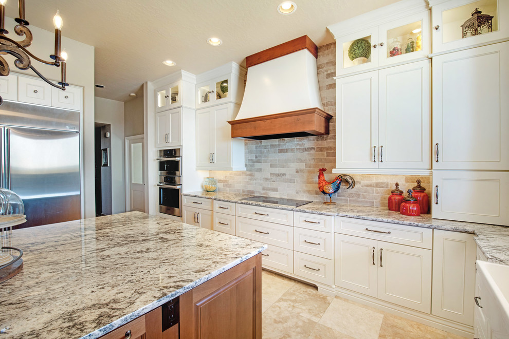 Open concept kitchen - large transitional u-shaped travertine floor and beige floor open concept kitchen idea in Phoenix with recessed-panel cabinets, white cabinets, granite countertops, an island, multicolored countertops, a farmhouse sink, gray backsplash, porcelain backsplash and stainless steel appliances